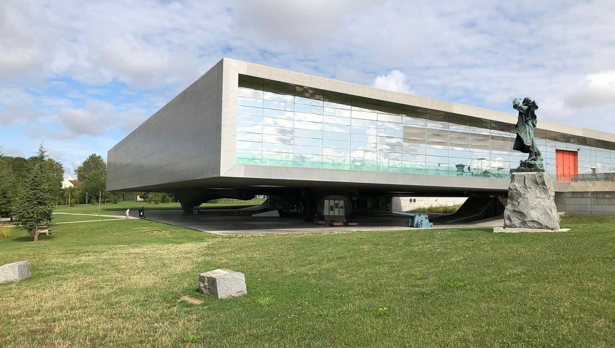 Un grand bâtiment avec une statue devant.
