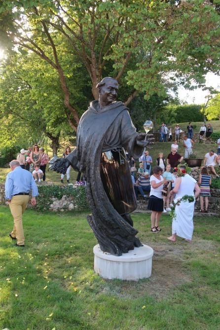 Un groupe de personnes se tient autour d'une statue d'un homme en robe.