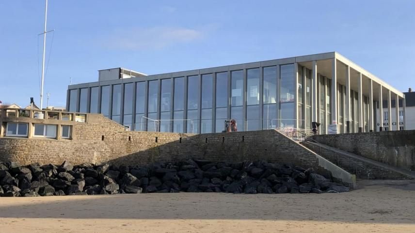 Un grand bâtiment avec beaucoup de fenêtres se trouve sur la plage.