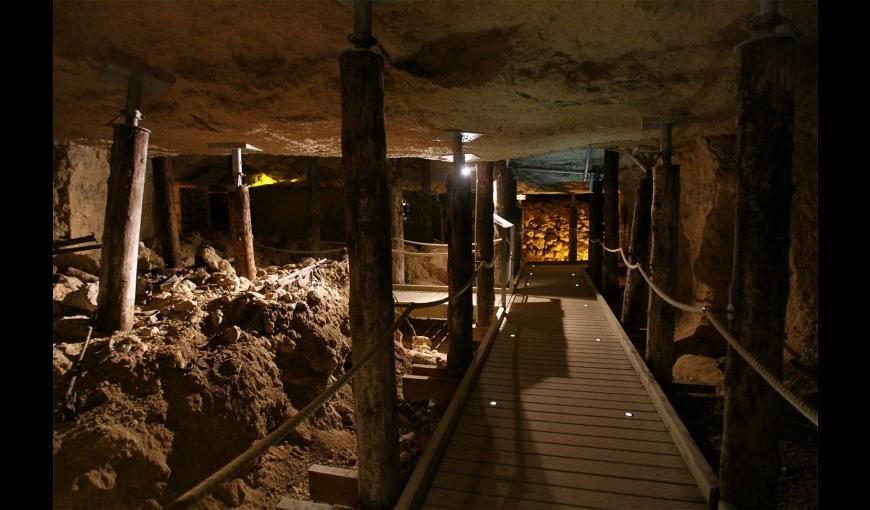 Une grotte sombre avec une passerelle en bois qui la traverse
