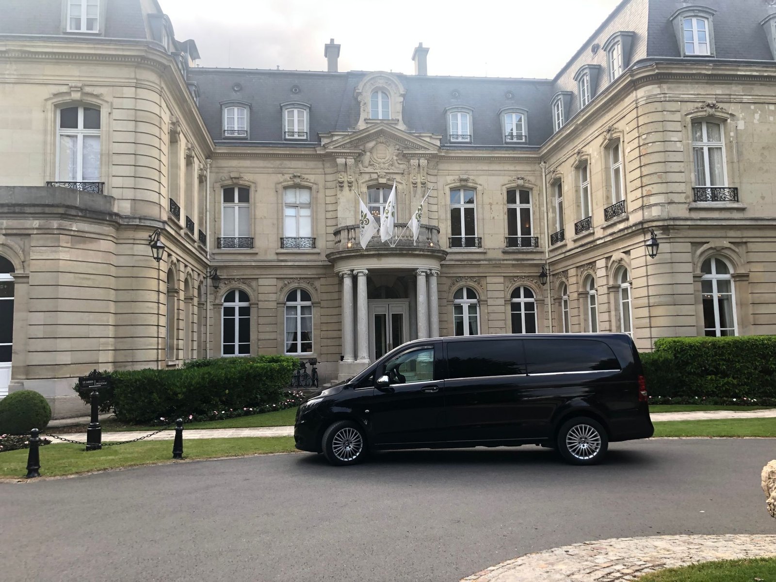 Une camionnette noire est garée devant un grand bâtiment.
