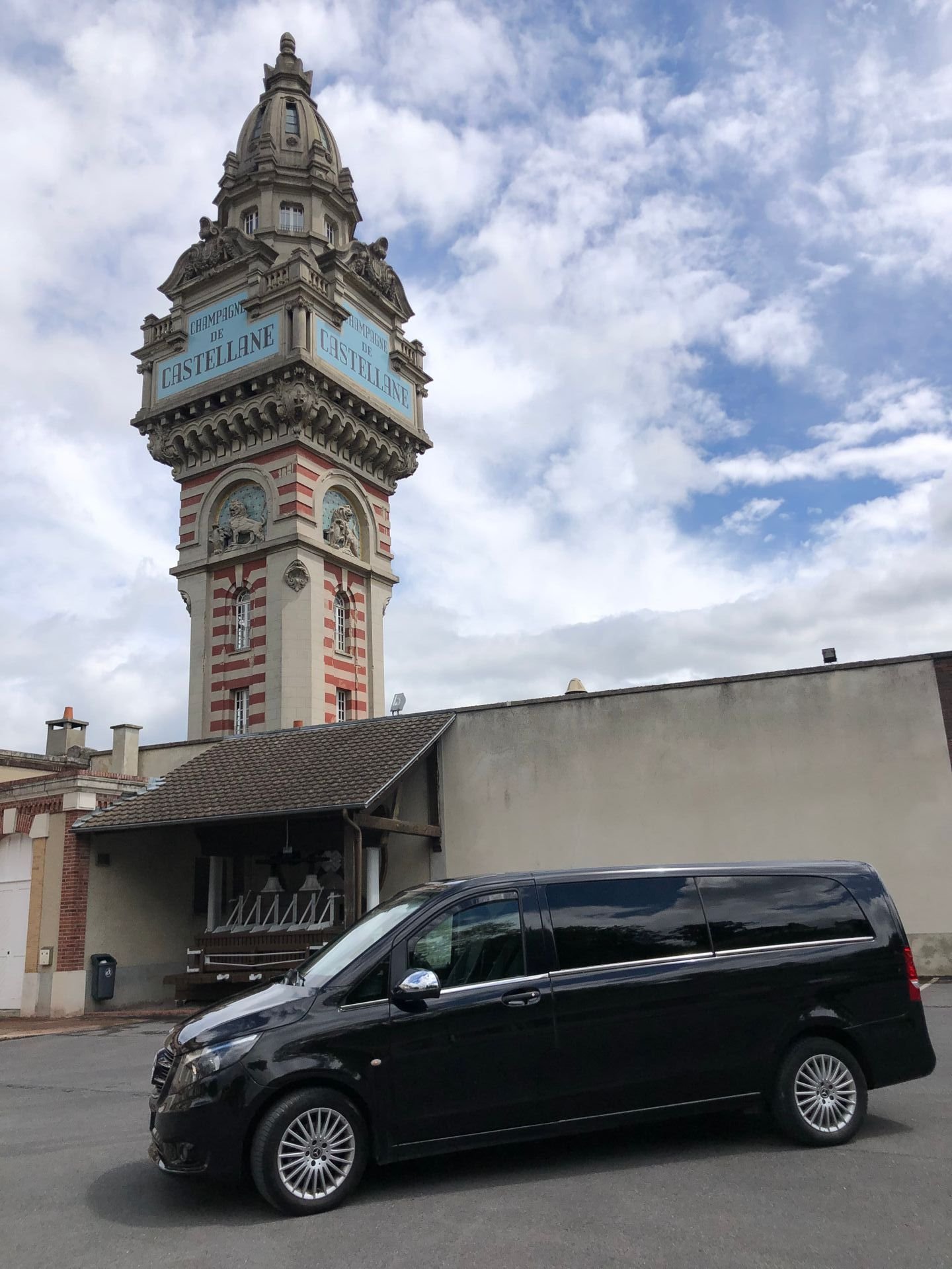 Une camionnette noire est garée devant une tour de l'horloge.