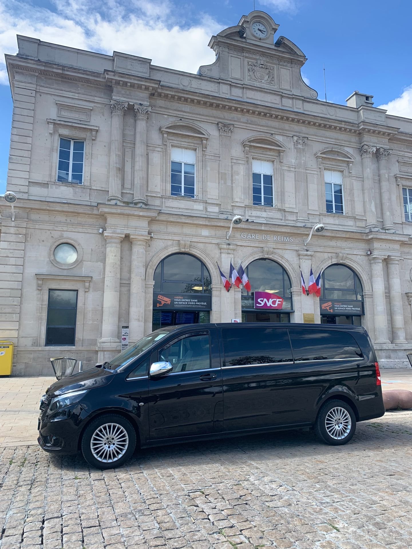 Une camionnette noire est garée devant un grand bâtiment.