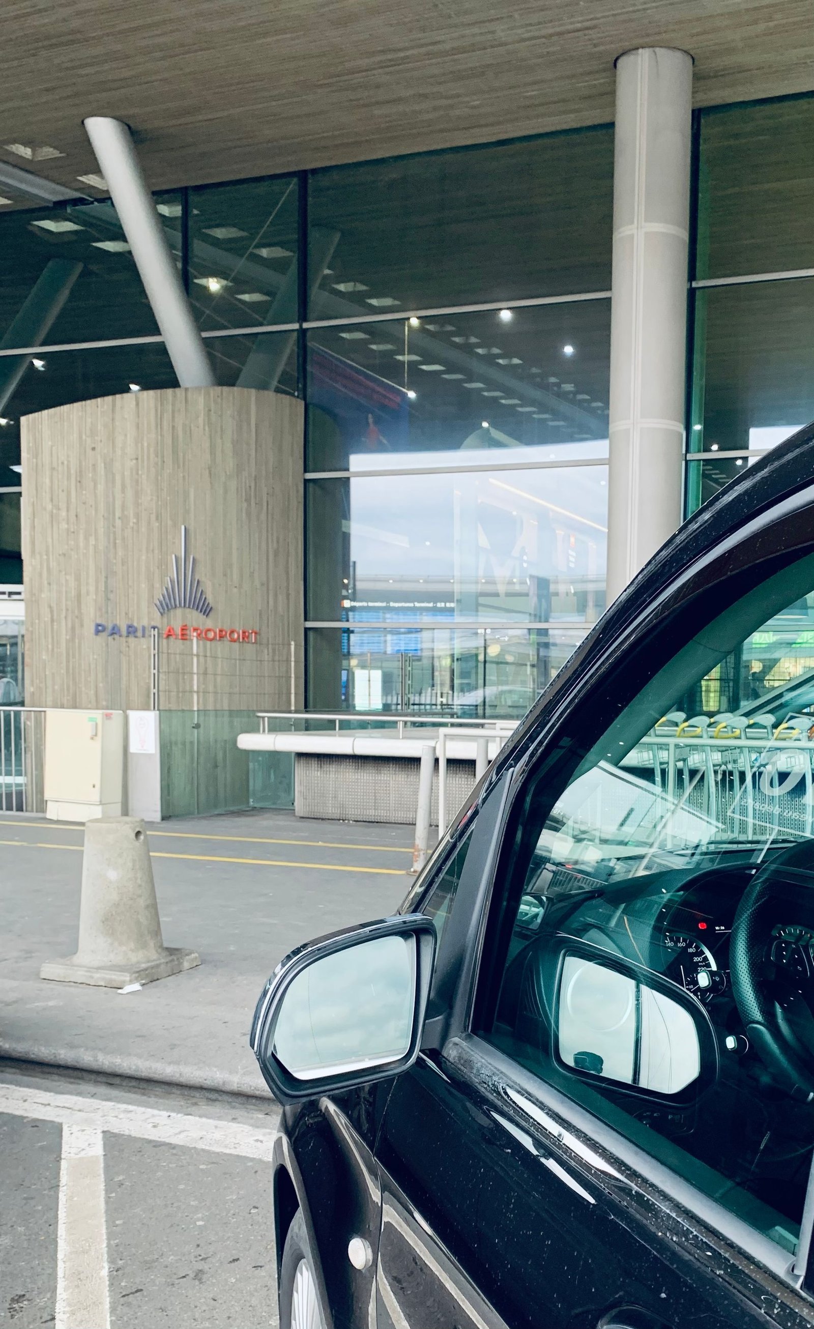 Une voiture noire est garée devant un aéroport.