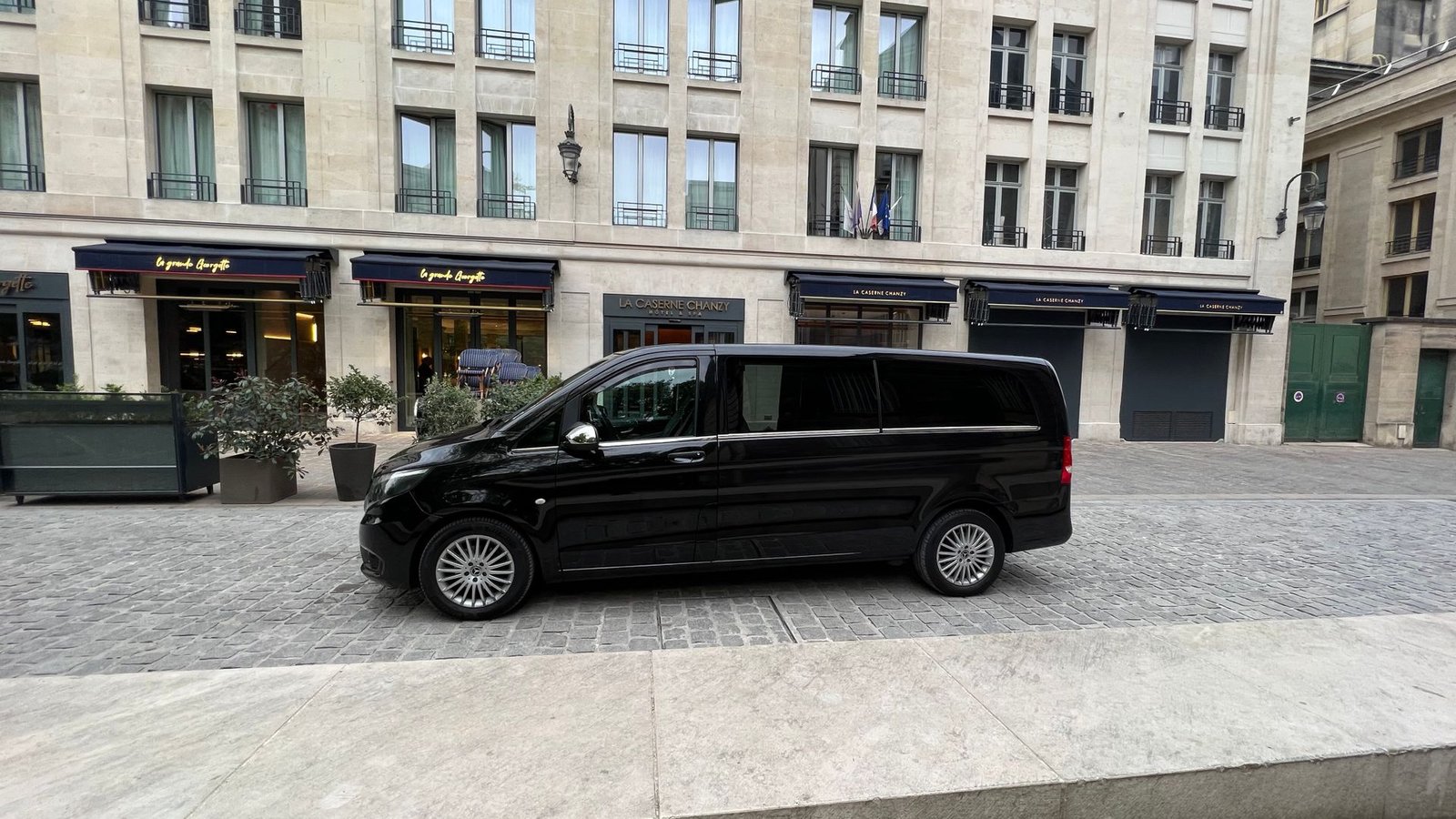 Une camionnette noire est garée devant un immeuble.