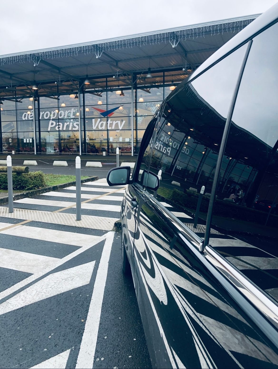 Une voiture noire est garée devant un aéroport