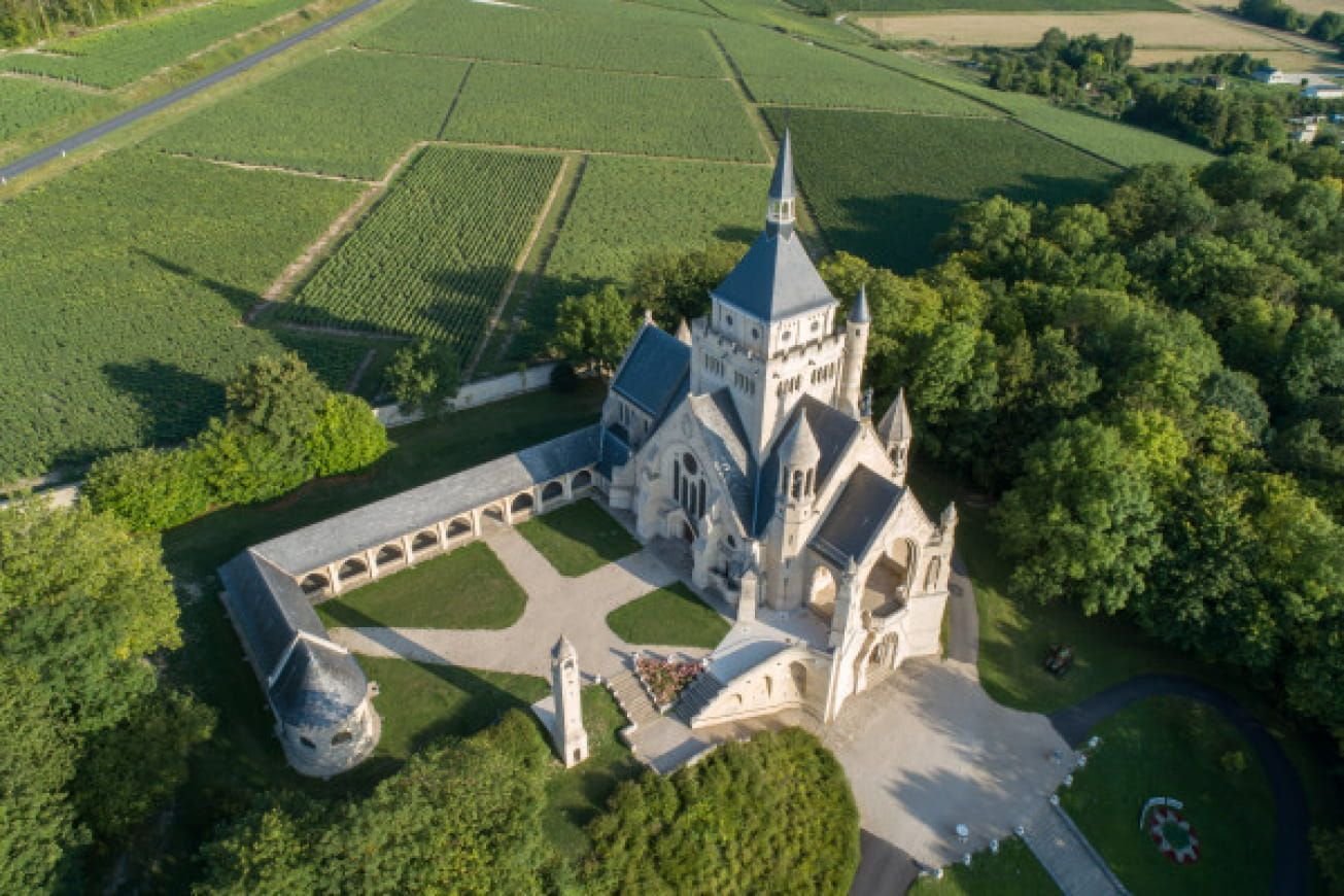 Une vue aérienne d'une grande église entourée d'arbres et de champs.