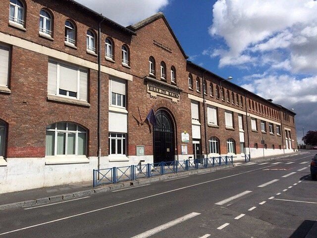 Un grand bâtiment en briques se trouve au bord d'une route.