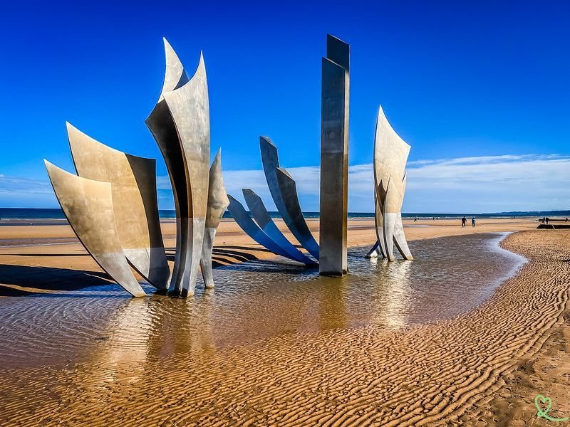 Un groupe de sculptures assises au sommet d'une plage de sable.