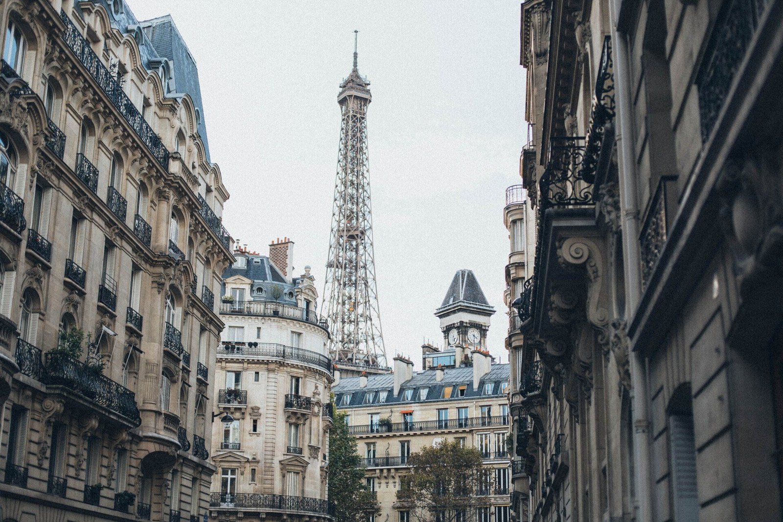 La tour eiffel est visible entre deux immeubles à paris